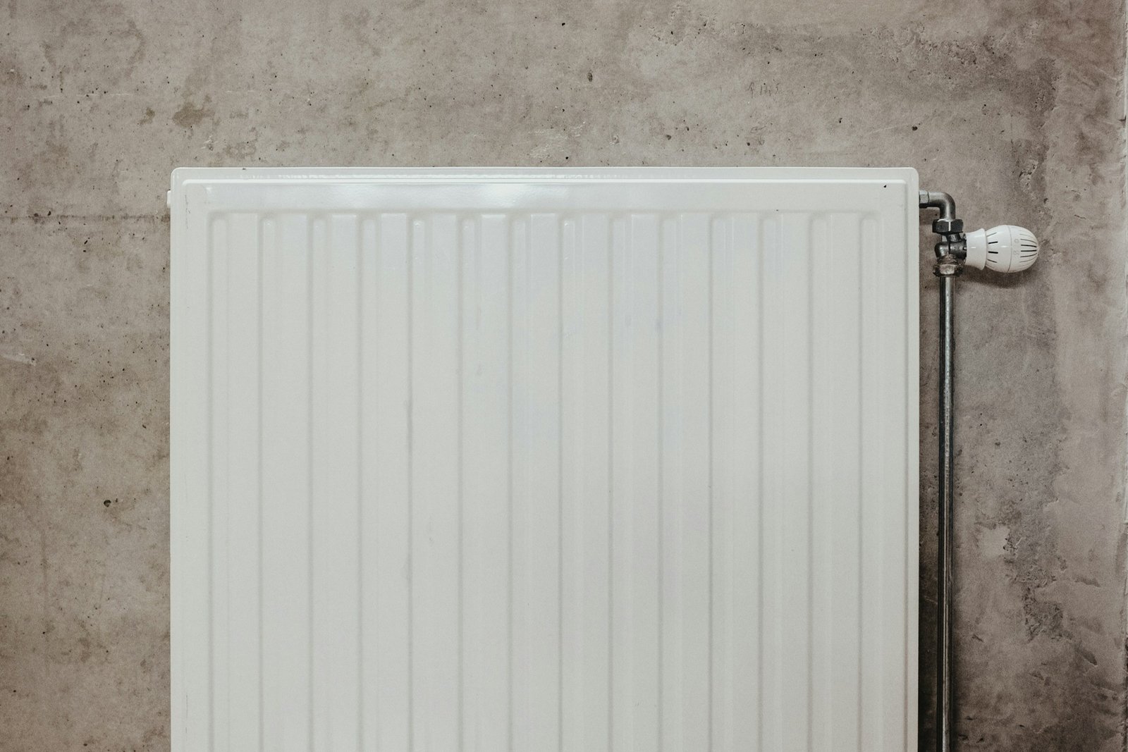 Kleiner Metallschlüssel vor einem Heizkörperventil